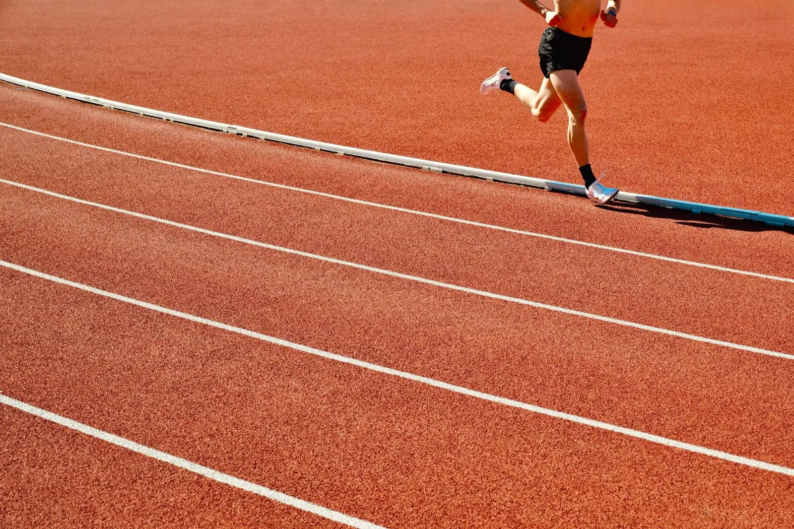 A lone runner mid-stride on an empty outdoor track